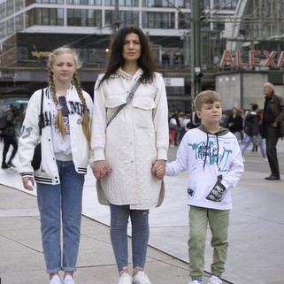 Frau mit zwei Kindern an den Händen auf dem Alexanderplatz in Berlin